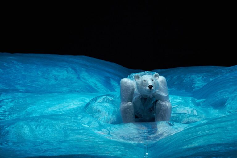 Een ijsbeer steekt zijn kop en schouders uit het water in een helder blauw zwembad.