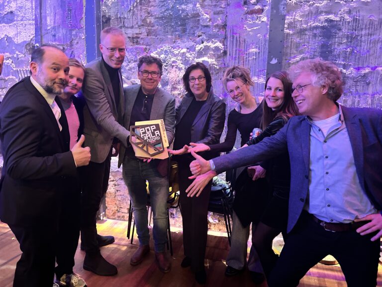 Een groep mensen poseert samen en toont een prijsplaquette aan de camera.