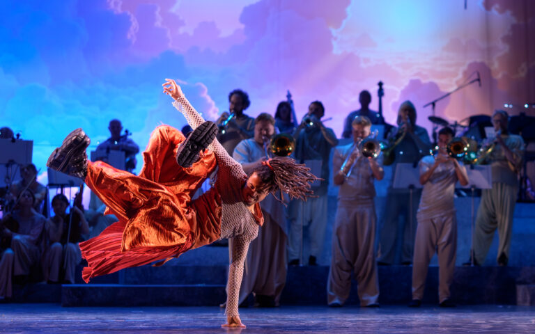 Man in oranje outfit die breakdance move doet