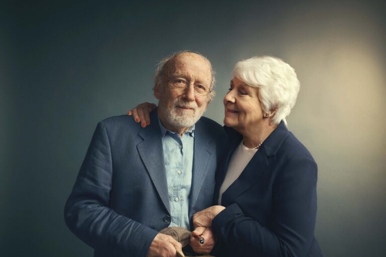 Een oudere man en een oudere vrouw staan dicht bij elkaar en glimlachen.