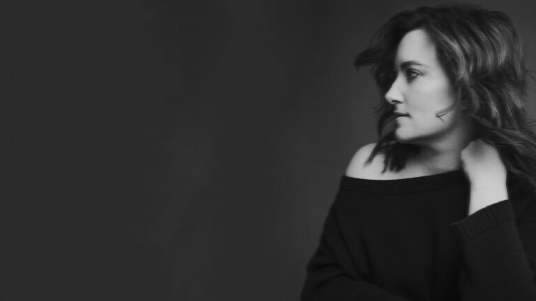 Een zwart-witportret van een vrouw met schouderlang haar, kijkend over haar rechterschouder.