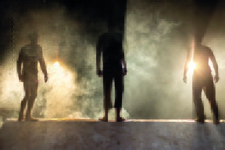 Silhouetten van mensen op een rookachtige podiumscène, met een vlam aan de linkerzijde.