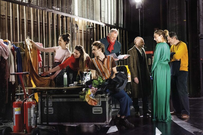 Een groep muzikanten staat rondom een vleugelpiano tijdens een repetitie.