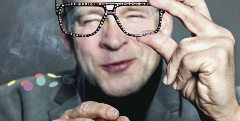 Close-up van een persoon die een bril met een stippenpatroon vasthoudt.