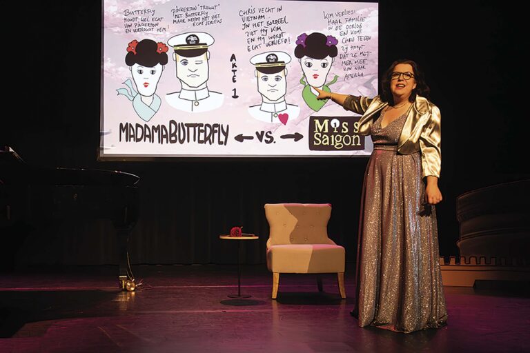 Een vrouw in een lange, glanzende jurk staat op een podium naast een projectiescherm met cartoonfiguren en tekst.