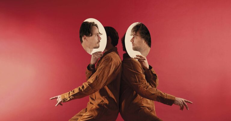 Twee mensen in bruine jassen staan rug aan rug op een roze achtergrond, met ronde portretten als gezichten.