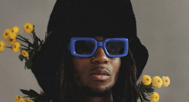 Portret van een persoon in een zwarte hoodie met een felblauwe zonnebril.