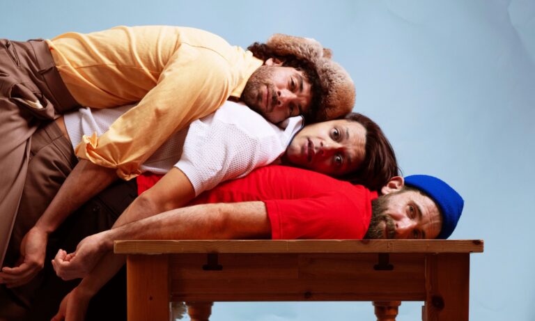 3 personen liggend op elkaar op een tafel