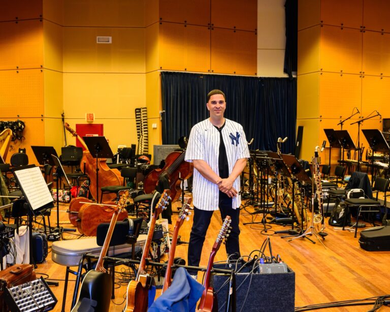 Vrolijke man in strepen blouse wordt omringd door instrumenten van het orkest.