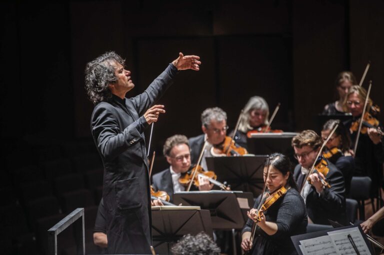 Een dirigent staat voor een orkest en dirigeert tijdens een optreden.