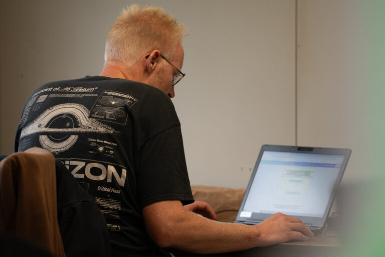 Marketeer Aldwin zit achter een laptop te werken in container tijdens Summerstage.