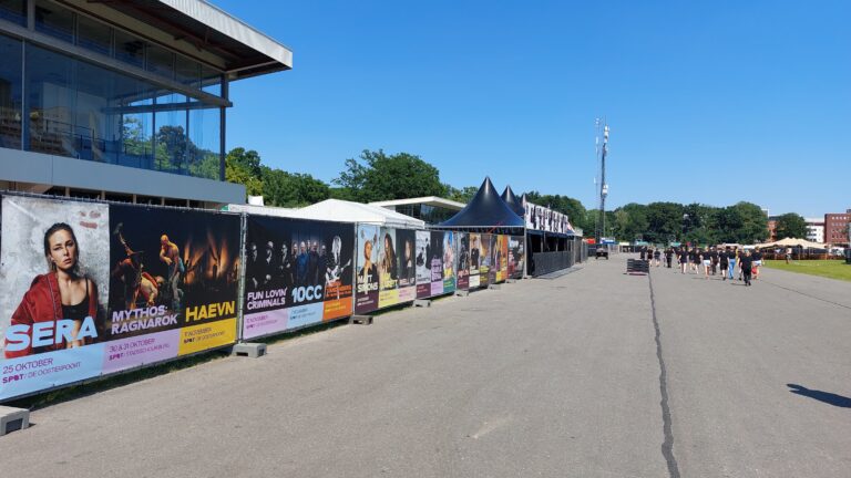 Lange rij met banners die opgehangen zijn bij Summerstage ter promotie van komende concerten en voorstellingen van SPOT Groningen.