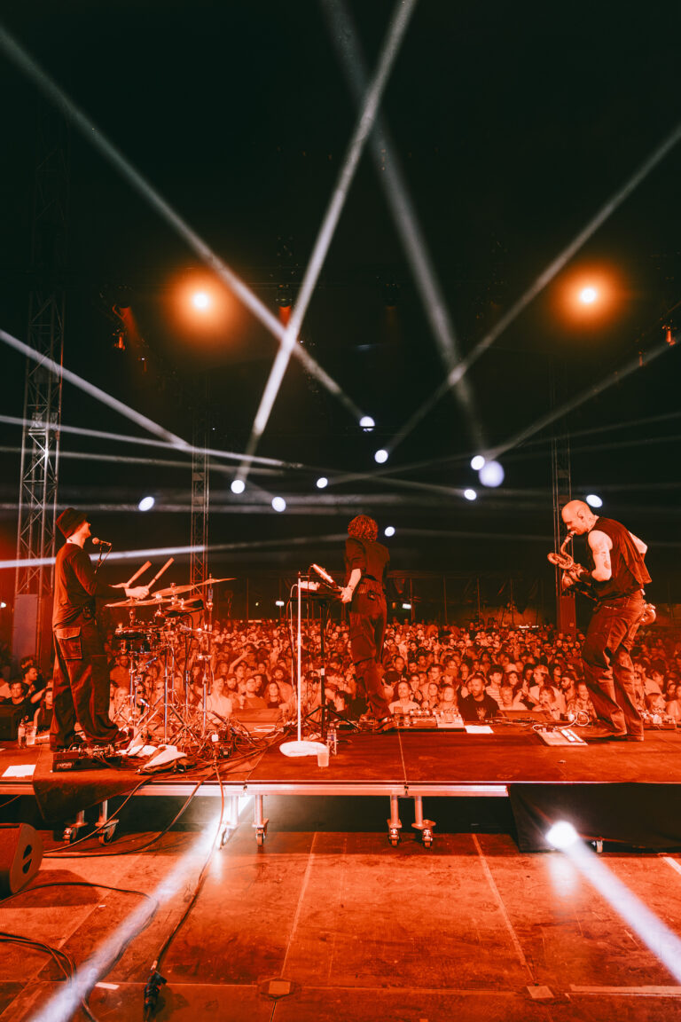 Drie roodverlichte mannen spelend richting het publiek.