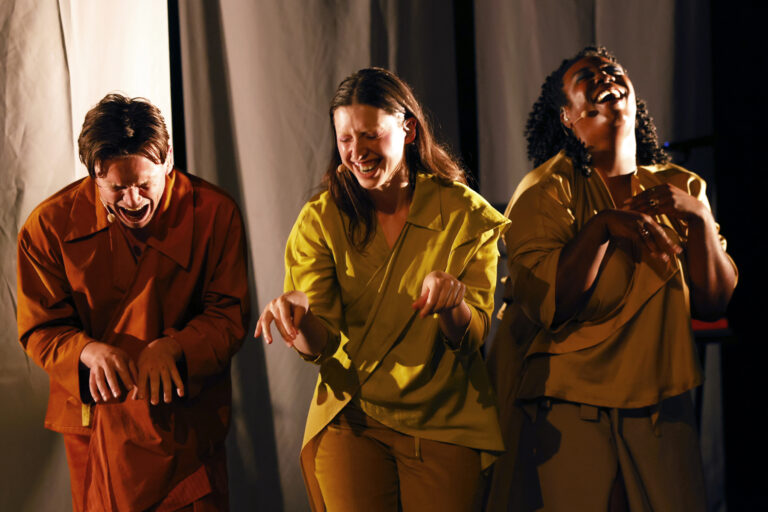 3 lachende personen in gele bruine outfits