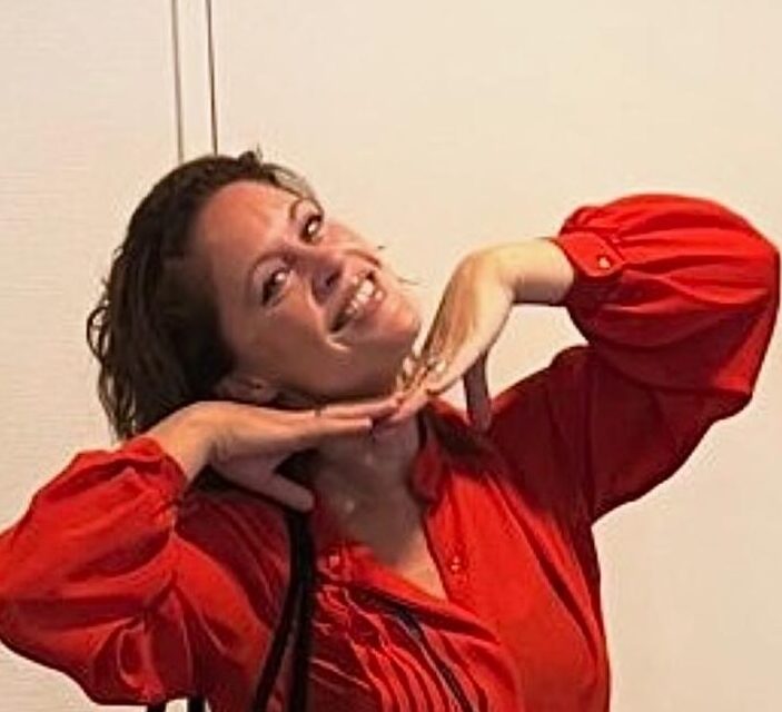 floormanager eva, lachend naar de camera, in een rood shirt