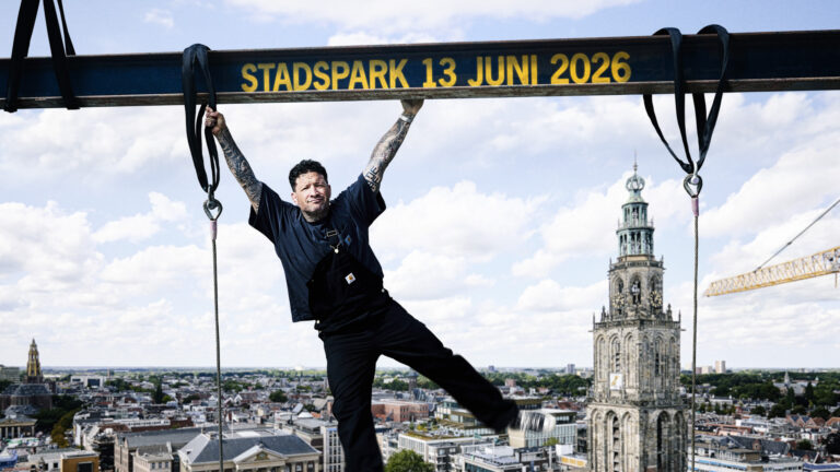 Kraantje Pappie hangt aan een kraan met in achtergrond de Martinitoren.
