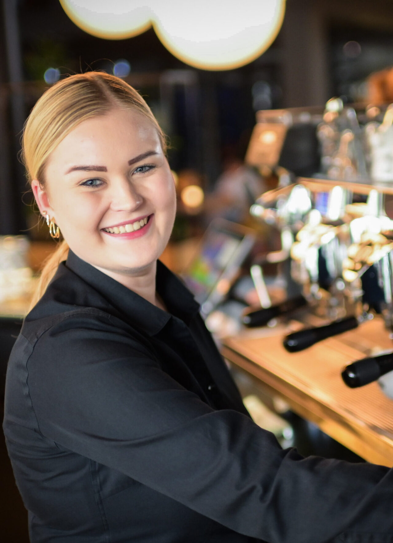 Horecamedewerker staat achter koffiezetapparaat.