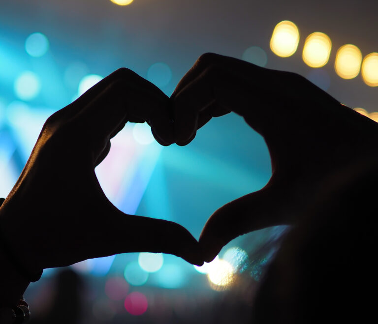 twee handen die samen komen in de vorm van een hartje, tijdens een concert