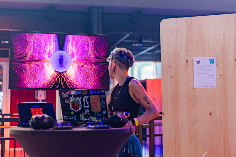 Een vrouwelijke DJ achter een mengpaneel met een kleurrijke LED-achtergrond.
