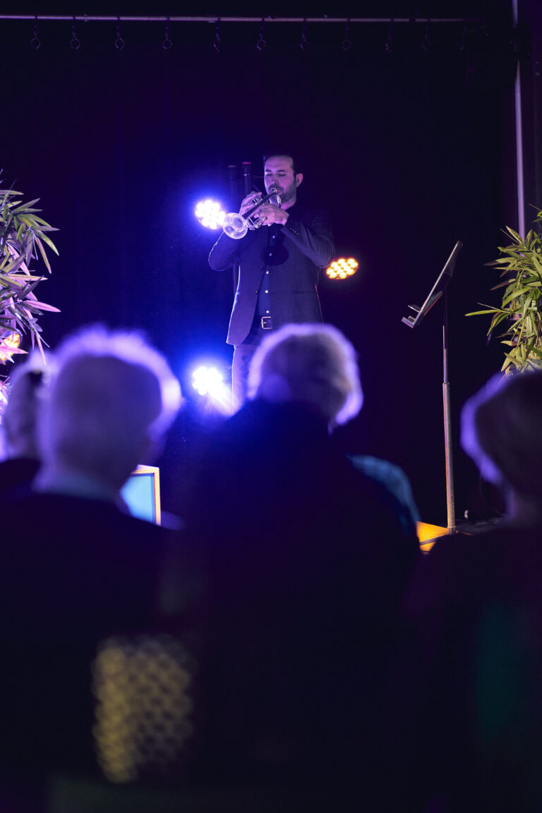 Trompetist in blauw jasje op een podium