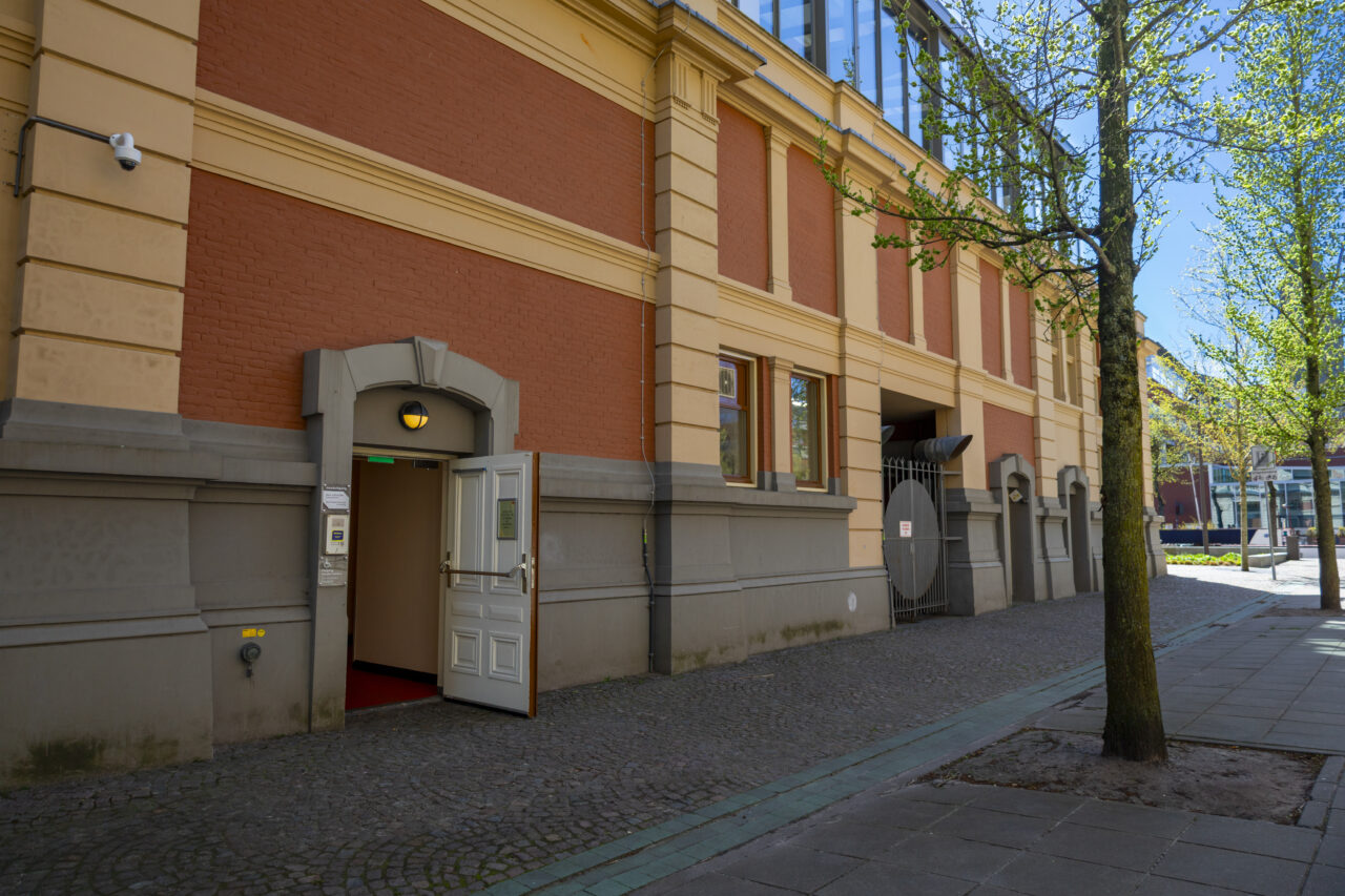 Deur aan de zijkant van de Stadsschouwburg met een boom ernaast.