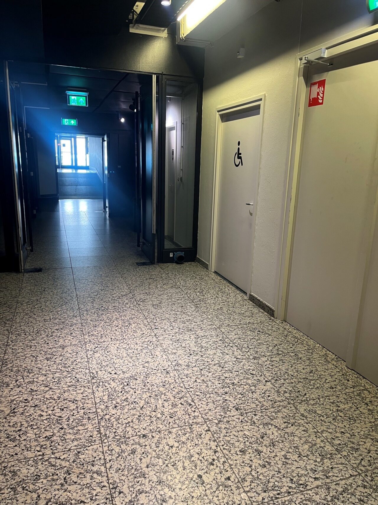 Lege gang met een wc deur met een rolstoel beeld erop.
