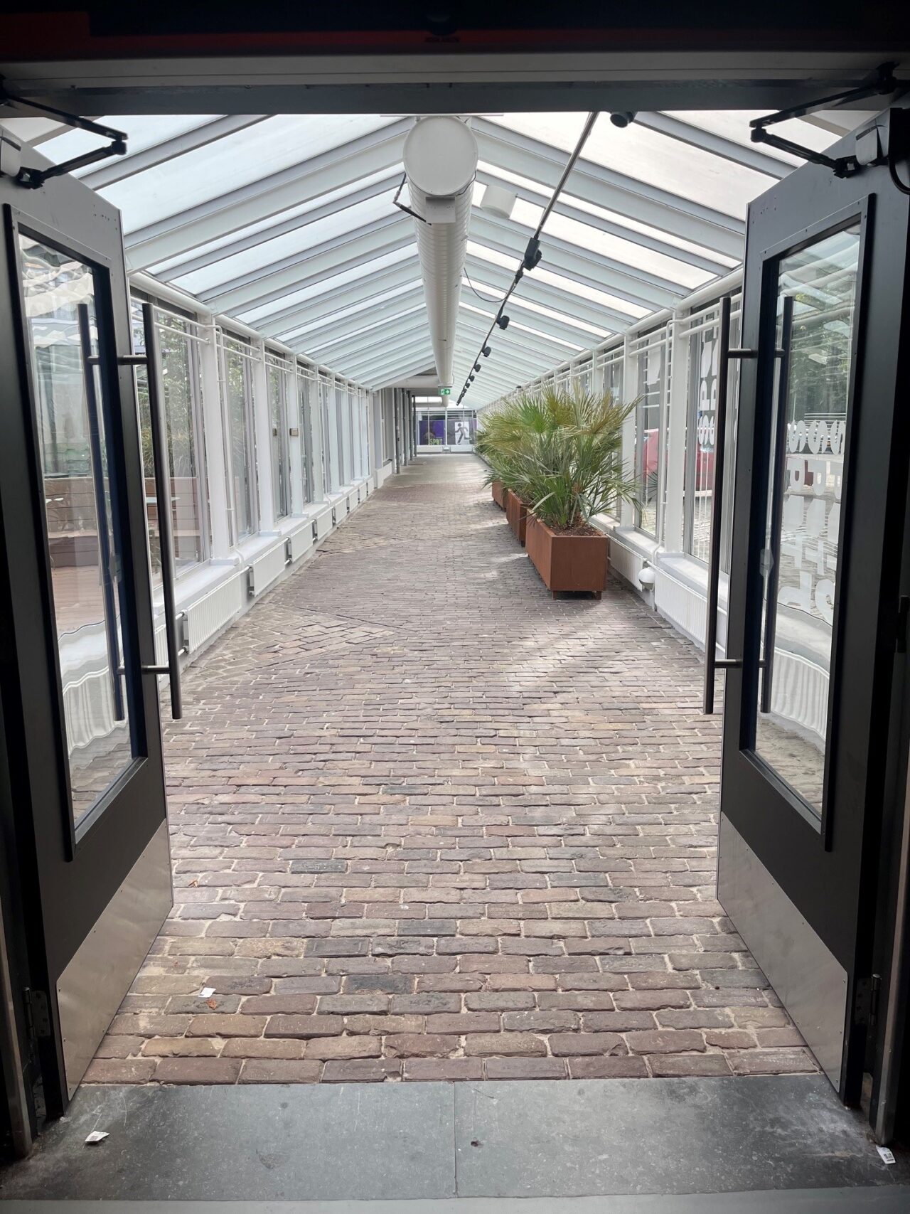 grote gang met klinkers op de grond en glazen muren en plafond.